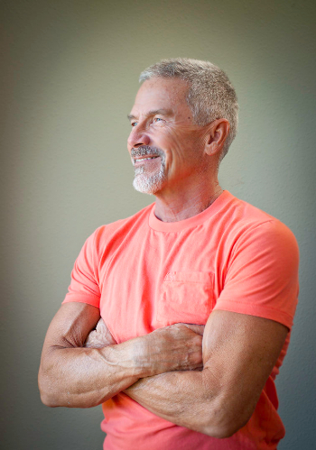 Michael G in an orange shirt with crossed arms